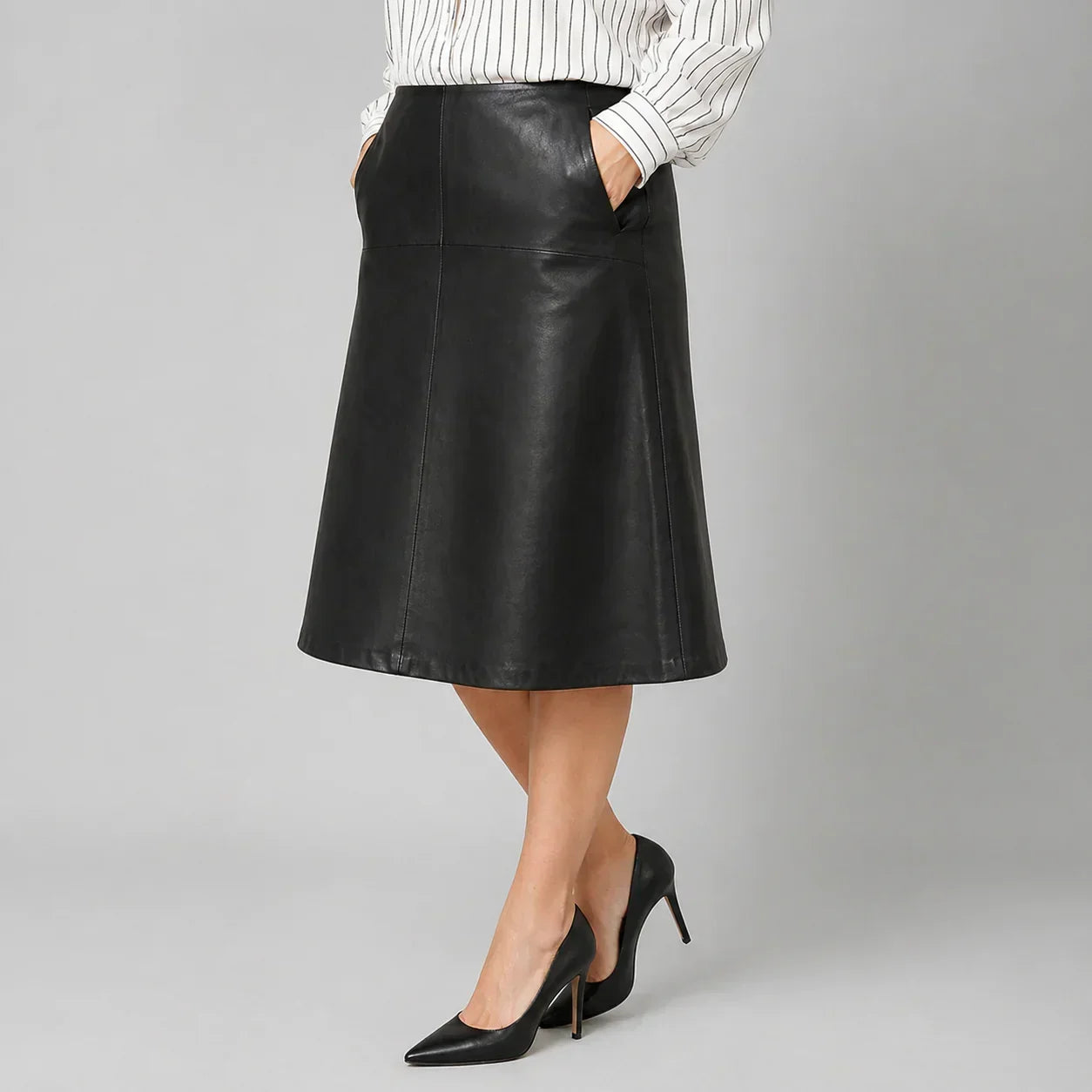 Woman wearing black genuine leather A-line skirt with pockets and black high heels