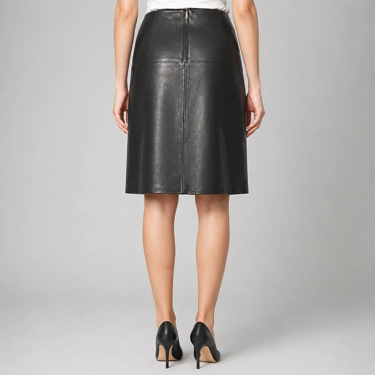 Woman wearing black genuine leather skirt and black heels, rear view, studio background
