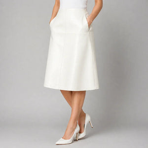 White genuine leather A-line skirt with side pockets, styled with white heels