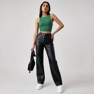 Woman wearing black genuine leather pants, green crop top, and white sneakers